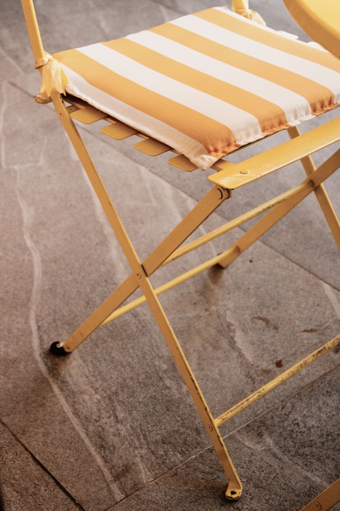 Crafting Captivating Headlines: Your awesome post title goes here Charming yellow folding chair with a striped cushion on stone flooring, ideal for patios.