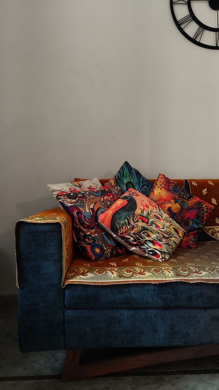 Mastering the First Impression: Your intriguing post title goes here A blue couch adorned with colorful, patterned cushions, creating a cozy and artistic atmosphere.