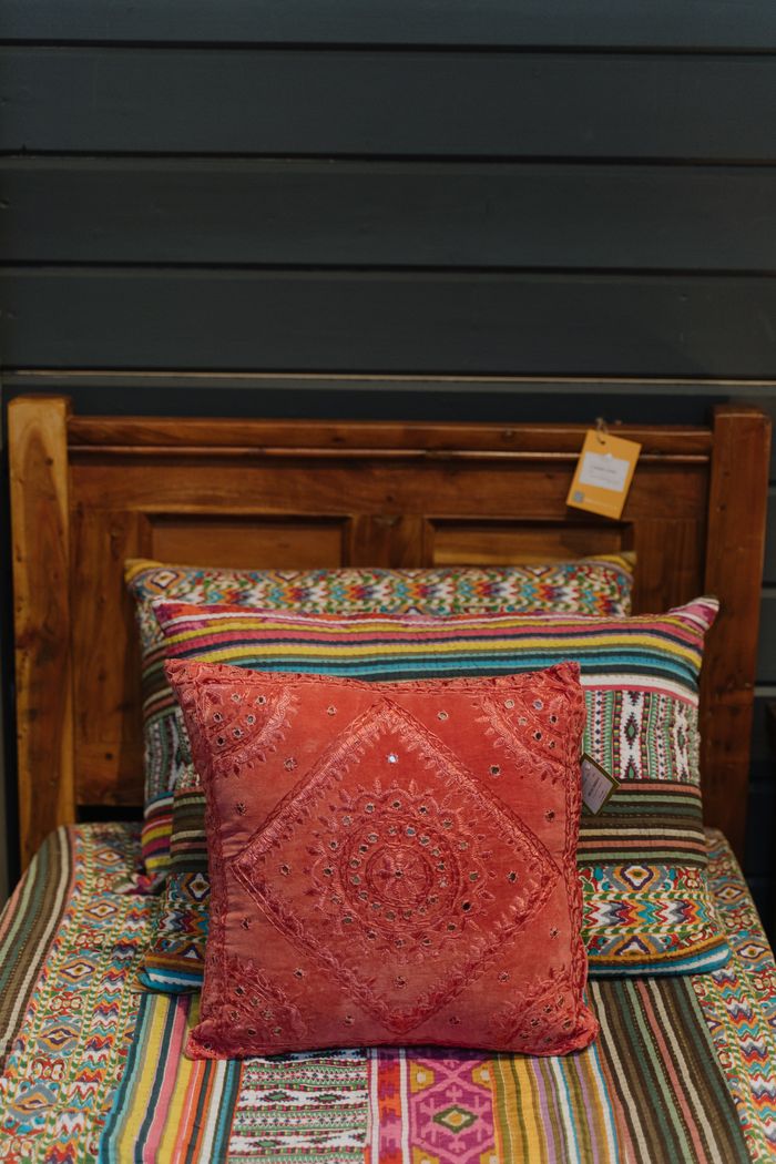 about-us Vibrant bed setup with colorful pillows and ethnic patterns in a cozy bedroom.