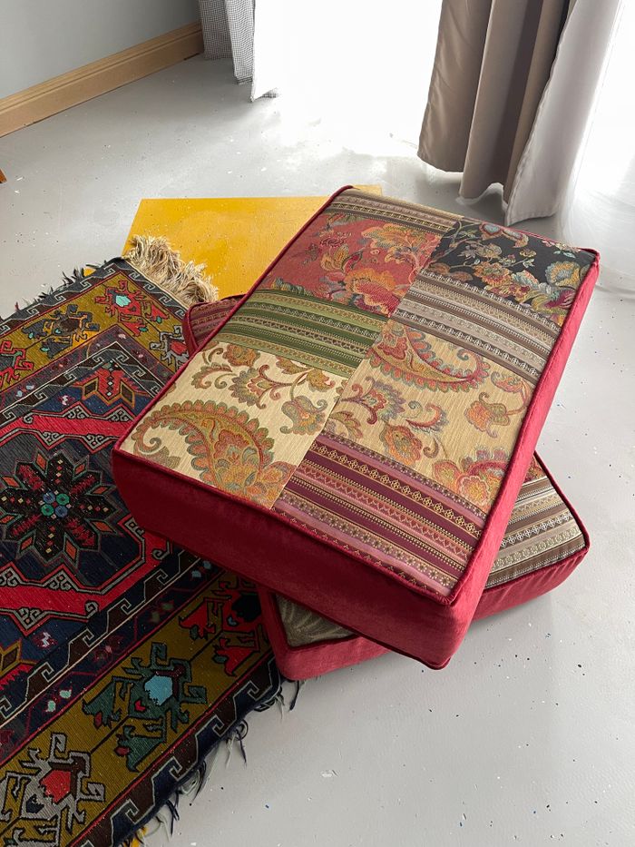 our-story Vibrant patchwork cushions on a detailed patterned carpet, perfect for eclectic decor ideas.